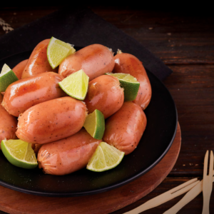 Butifarras cocidas en plato negro con gajos de limón fresco y tenedores de madera.