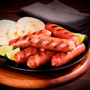 Chorizos mini santarrosanos a la parrilla con arepas asadas y gajos de limón.