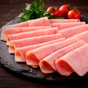 Lonchas de jamón de cerdo en abanico sobre tabla de pizarra con tomates cherry y perejil.