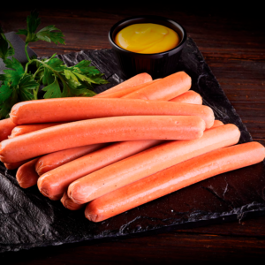 Salchichas para perro caliente sobre tabla de pizarra con mostaza y perejil fresco.