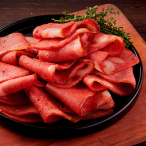 Lonchas de tocineta ahumada enrolladas en plato negro con tomillo fresco.